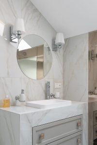 Modern bathroom interior with wall mirror and chrome tap above stone countertop